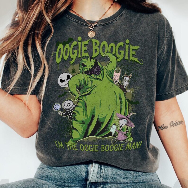May include: Dark gray t-shirt featuring a green graphic of Oogie Boogie from The Nightmare Before Christmas, with the text "Oogie Boogie" and "I'm the Oogie Boogie Man!". The design includes other characters from the film.
