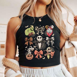 May include: Black tank top featuring a colorful graphic of characters and bows from The Nightmare Before Christmas. The design includes Jack Skellington, Sally, Oogie Boogie, and other iconic elements from the movie.