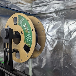 May include: A black filament spool mounted on a black filament holder. The spool is labelled "OVERTURE PLA 3D PRINTER FILAMENT".