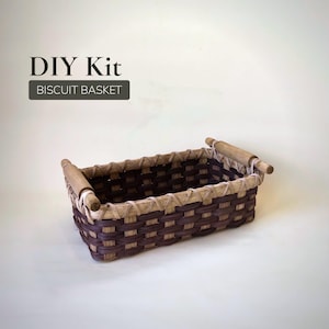 May include: A rectangular biscuit basket DIY kit. The basket is woven with alternating dark brown and tan strips. It has wooden handles on each end and the text "DIY Kit BISCUIT BASKET" is displayed above the basket.