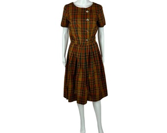 Könnte beinhalten: Ein braunes, rotes und grünes kariertes Kleid mit kurzen Ärmeln und Knopfleiste. Das Kleid hat einen Faltenrock und ist tailliert.