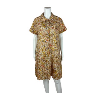 May include: A short-sleeved, button-down dress with a white background and a colorful abstract print. The dress has a pleated skirt and a collared neckline.