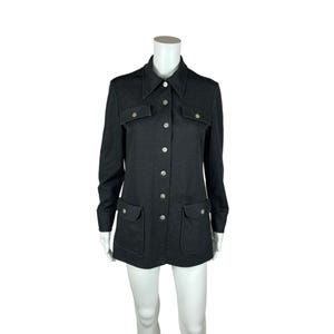 May include: A long-sleeved, dark gray collared shirt with a button-up front and two flap pockets. The shirt has a slightly textured fabric and silver buttons.