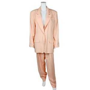 Puede incluir: Un traje de color melocotón con una chaqueta y pantalones a juego. La chaqueta tiene un cierre de un solo botón y una solapa de muesca.