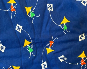 May include: Blue fabric with a repeating pattern of yellow, green, and red stick figures holding kites with Japanese characters. The background is a solid blue.