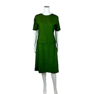 May include: A green two-piece skirt suit with a short-sleeved top and a knee-length skirt.