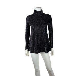 May include: A black, long-sleeved turtleneck top with a flared hem. The fabric has a subtle, shimmering texture. The top is displayed on a mannequin against a white background. The garment is a women's top.
