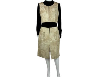May include: A two-piece outfit featuring a beige suede vest and skirt. The vest has a zipper closure and the skirt has two pockets.