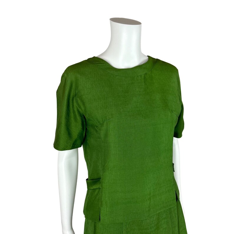 May include: A green short-sleeved dress with a round neckline and a skirt with pockets.