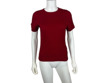 May include: A short-sleeved, ribbed knit top in a deep red hue. The shirt has a crew neck and a form-fitting silhouette. The fabric appears to be a soft, lightweight material, suitable for warmer weather.