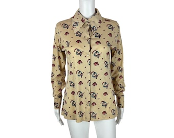 May include: A beige long-sleeved button-up shirt with a colourful geometric pattern. The shirt has a collared neckline and a button-up front.