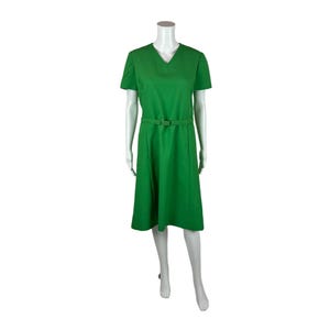 Könnte beinhalten: Ein grünes, kurzärmeliges Kleid mit V-Ausschnitt und Gürtel.