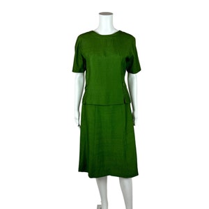 May include: A green two-piece skirt suit with a short-sleeved top and a knee-length skirt.