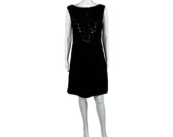 May include: A black sleeveless dress with a beaded neckline. The dress is knee-length and has a simple, elegant design.