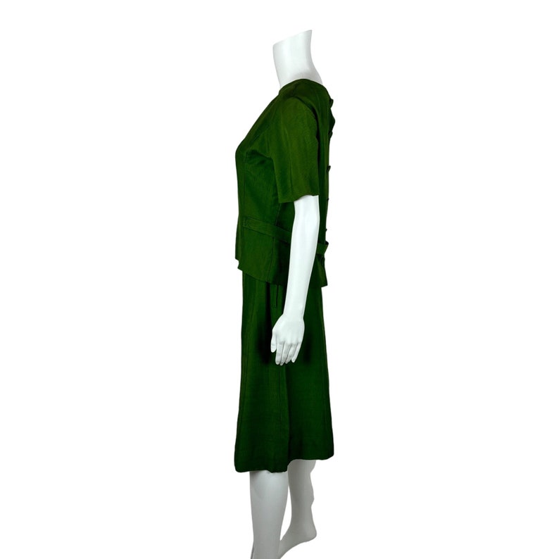 May include: A dark green skirt suit with a short-sleeved top and a knee-length skirt.