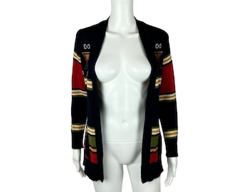 May include: A navy blue cardigan with a striped pattern in red, green, and cream. The cardigan has a geometric design on the front and is open in the front.