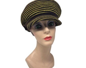 May include: A brown and gold striped newsboy cap with a small brim. The hat is displayed on a mannequin head. The cap features horizontal stripes in a dark brown and gold color scheme. The hat is a stylish accessory.