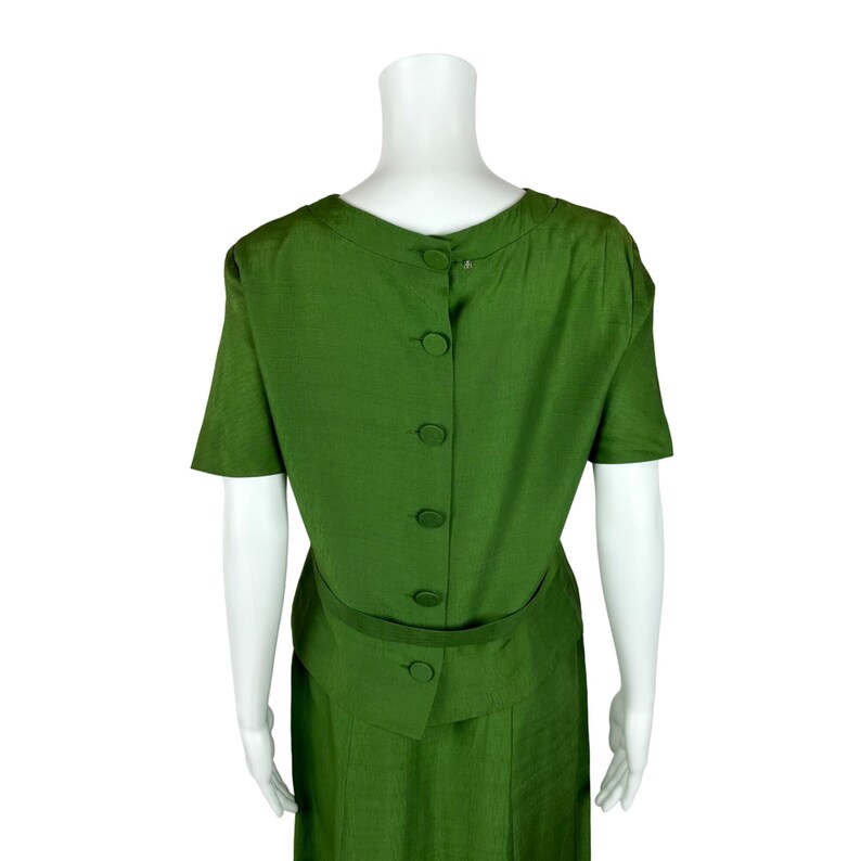 May include: A green dress with a button-up back and a belt. The dress has short sleeves and a skirt that falls to the knees.