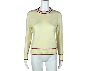 May include: A cream-colored sweater with a red and white trim around the neckline and hem. The sweater is made of a soft, fuzzy material.