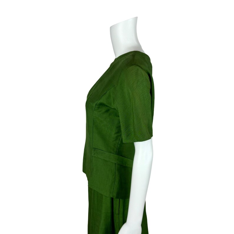 May include: A green short-sleeved dress with a skirt and a fitted bodice. The dress is on a white mannequin.