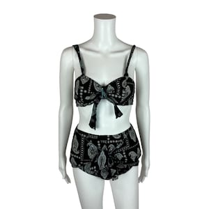 May include: Black and white paisley print bikini top and bottom. The top has a bow at the front and the bottom has a high waist.