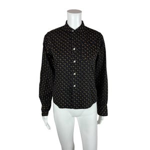 May include: A black long-sleeved button-up shirt with a small gold cross pattern.