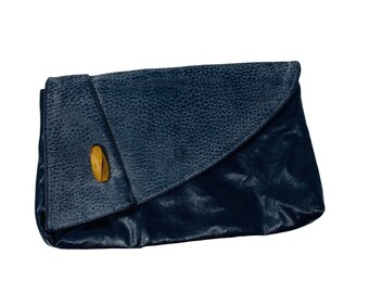 May include: A dark blue leather clutch with a wooden button closure.