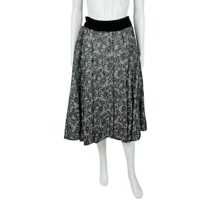 May include: A black and white patterned midi skirt with a black waistband. The skirt is pleated and has a flared silhouette.