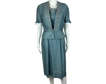 May include: A light blue dress suit with a white embroidered neckline and short sleeves.