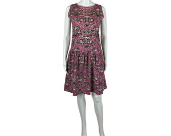 May include: A sleeveless pink dress with a black and white patterned design. The dress has a round neckline and a flared skirt.