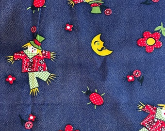May include: A blue denim fabric with a repeating pattern of scarecrows, ladybugs, moons, and flowers. The scarecrows are wearing red and white checkered shirts and green pants. The ladybugs are red with black spots. The moons are yellow with black eyes and a smile. The flowers are red with yellow centers.
