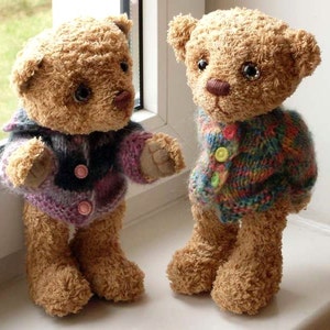 May include: Two brown teddy bears wearing knitted sweaters. One bear is wearing a purple and black sweater with pink buttons. The other bear is wearing a multi-colored sweater with yellow buttons.