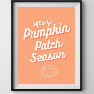 以下が含まれることがあります： 「Officially Pumpkin Patch Season」の文字が白で書かれた、カボチャのイラストが下部にある額装されたアートプリント。背景はピーチ色で、フレームは黒です。