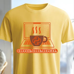 May include: Yellow t-shirt with a graphic featuring a laptop, a coffee cup with the Python logo, and the text "COFFEE. CODE. REPEAT." The laptop screen has a grid pattern, and steam rises from the coffee cup.