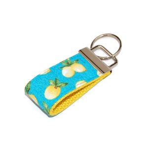 May include: A yellow and blue key chain with a lemon print. The key chain has a silver metal ring.