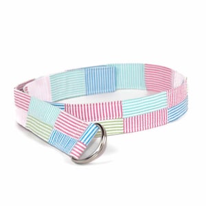 May include: A colorful striped fabric belt with a silver D-ring buckle. The belt is made of different colored stripes sewn together in a patchwork pattern.