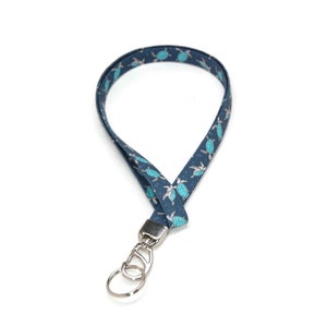 May include: A blue lanyard with a silver key ring and a pattern of sea turtles.