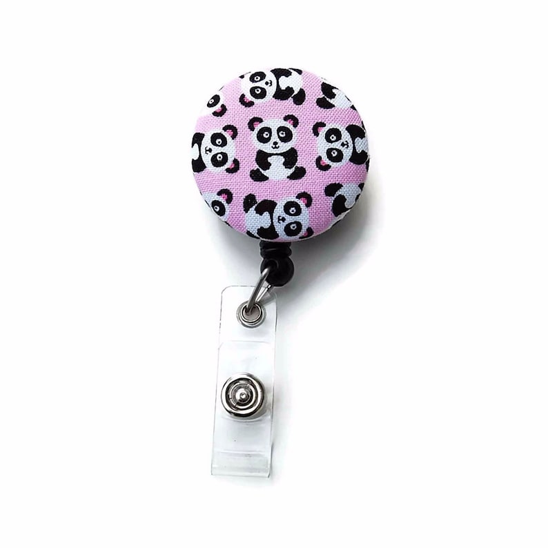 Puede incluir: Un portagafete retr&aacute;ctil rosa y negro con un patr&oacute;n de oso panda. El portagafete tiene un clip de pl&aacute;stico transparente y un cord&oacute;n retr&aacute;ctil negro.