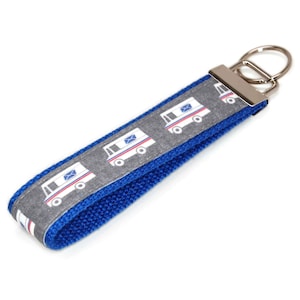 May include: A blue and gray key chain with a silver key ring. The key chain has a repeating pattern of white mail trucks with red and blue accents.