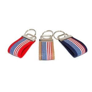 May include: Three keychains with red, white, and blue striped fabric. The keychains are made of metal and fabric.