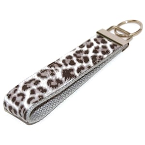 May include: A gray and white leopard print key chain with a silver key ring.