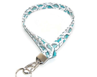 May include: White lanyard with a blue dinosaur pattern and a silver swivel clip.