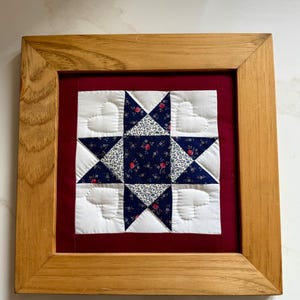 Hand-stitched, framed in wood, mini quilt featuring a Starry Nine Patch block pattern