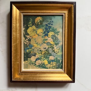 May include: A rectangular wall art piece featuring a vibrant floral bouquet in a vase, set against a landscape background. The artwork is encased in a thick, ornate frame with a dark brown outer edge and a bright, reflective gold inner border.