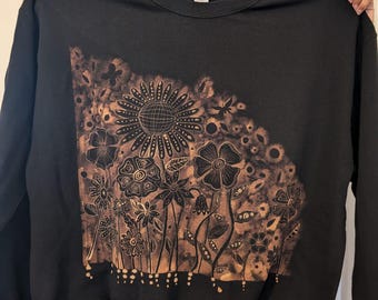 Sudadera negra personalizada con diseño de flores y garabatos en lejía. Hecha a mano y por encargo. Diseño en la parte delantera.