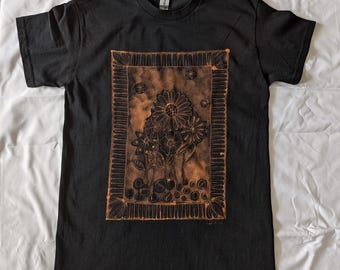 Diseño de garabato floral con marco blanqueado, hecho a medida, sobre camiseta negra. Diseño blanqueado frontal hecho a mano sobre camiseta negra. Hecho a pedido.