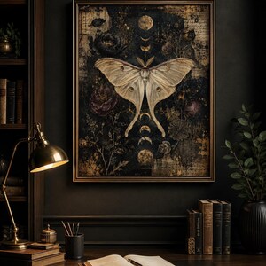 Puede incluir: Una impresi&oacute;n de arte mural rectangular enmarcada que presenta una gran polilla p&aacute;lida centrada sobre un fondo oscuro y texturizado. La obra incluye elementos florales de color p&uacute;rpura intenso, fases lunares doradas y texto manuscrito superpuesto.