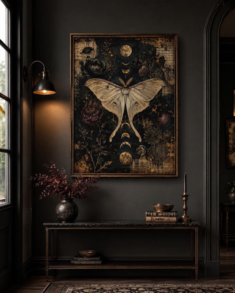 Puede incluir: Una impresi&oacute;n de arte mural rectangular enmarcada que presenta una gran polilla de color crema centrada sobre un fondo oscuro y texturizado. La obra incluye fases lunares doradas, elementos bot&aacute;nicos y texto escrito, todo en un marco de bronce.