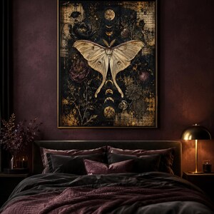 Puede incluir: Una l&aacute;mina de arte mural enmarcada que muestra una polilla grande y p&aacute;lida centrada sobre un fondo oscuro y texturizado. La composici&oacute;n incluye fases lunares doradas, elementos florales dispersos y texto tenue en tonos negros, dorados y marrones.