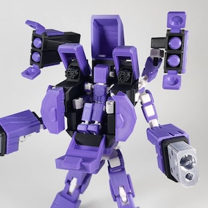 May include: A purple and black robot action figure with silver gun-like attachments on its arms. The toy has a detailed design with articulated joints and a futuristic aesthetic. The robot is standing against a plain white background.